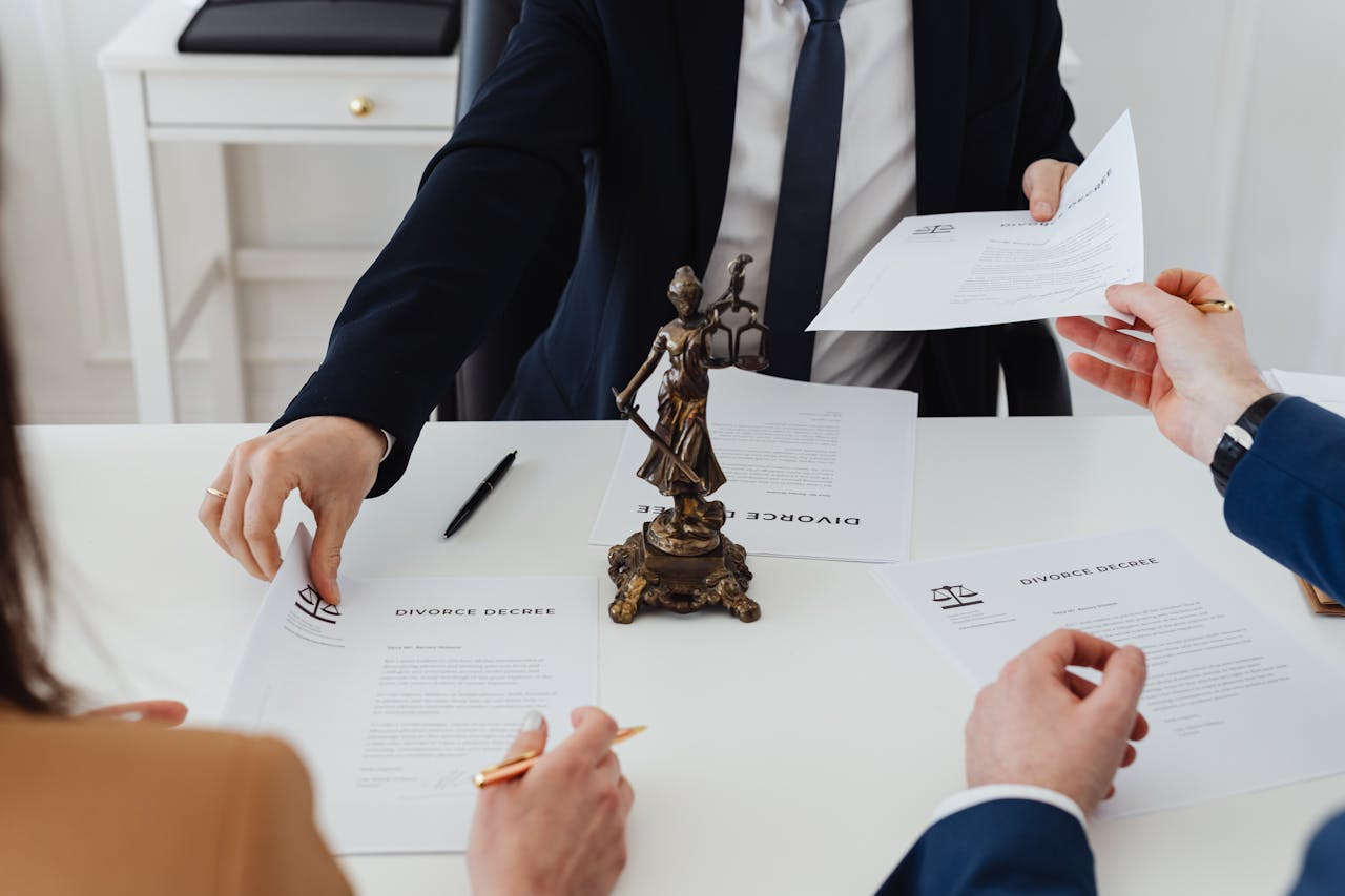 About Three adults discussing divorce documents in a formal office setting with legal statue in view.